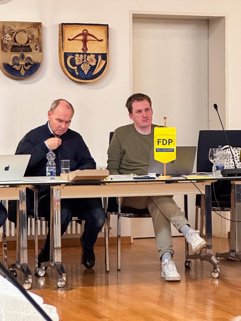Männer bei politischer Veranstaltung mit FDP-Logo